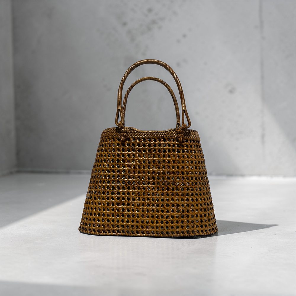 Woven rattan handbag against a concrete wall